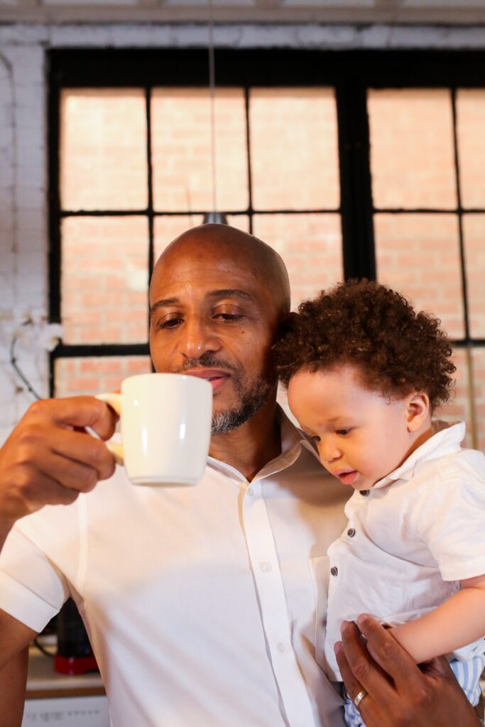 Father drinking tea holding toddler